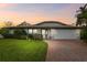 Charming single-story home featuring a brick driveway, lush lawn, and well-maintained landscaping at 1508 Cascade Ct, Dunedin, FL 34698
