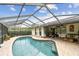 A screened-in pool features red brick trim, an outdoor living space, and an open-air feel at 1508 Cascade Ct, Dunedin, FL 34698