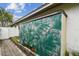 Exterior view of a storage shed with green tropical-themed painting and side access to the home's backyard space at 1508 Cascade Ct, Dunedin, FL 34698