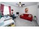 Inviting room with red sofa, desk area, and comfortable carpeting under a ceiling fan at 19573 Ship Wheel Way, Land O Lakes, FL 34638