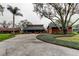 Charming exterior view of a well-maintained house with a spacious driveway, lush landscaping, and mature trees at 22819 Southshore Dr, Land O Lakes, FL 34639