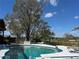 Beautiful pool with blue tile, lounge chair, and scenic view of trees and lake at 22819 Southshore Dr, Land O Lakes, FL 34639