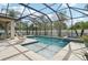 Screened pool featuring a waterfall, in ground spa, and travertine deck offering relaxing outdoor entertainment at 2515 Sherman Oak Dr, North Port, FL 34289