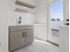Functional mud room with gray cabinets, floating shelves, sink, and a door to an outdoor space at 307 15Th N St, St Petersburg, FL 33705