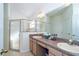 Well-lit bathroom featuring double sinks and a glass-enclosed shower at 31826 Larkenheath Dr, Wesley Chapel, FL 33543