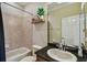 Cozy bathroom featuring tile floors, a shower/tub combo, and a wooden shelf with decorative plants and a clock at 3339 Diamond Falls Cir, Land O Lakes, FL 34638