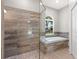 Bathroom featuring a glass-enclosed shower, soaking tub, and tile accents at 405 Tennessee Ave, Crystal Beach, FL 34681