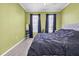 A bedroom with light green walls, a large bed, and two windows with black curtains at 4221 W Spruce St # 1407, Tampa, FL 33607
