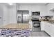 Modern kitchen featuring white cabinets, stainless steel appliances, and stylish island with granite counters at 4221 W Spruce St # 1407, Tampa, FL 33607