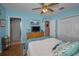 Comfortable bedroom featuring a ceiling fan, blue walls, wood floors and ensuite bathroom access at 4677 Aylesford Dr, Palm Harbor, FL 34685