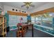 Well-lit home office includes tropical wall, desk with seating, and window with blinds at 4677 Aylesford Dr, Palm Harbor, FL 34685
