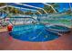 Clear blue pool with a spa, surrounded by a screened enclosure and lush greenery at 4677 Aylesford Dr, Palm Harbor, FL 34685
