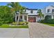 Charming two-story home features a lush landscaped yard, brick driveway, and inviting front porch at 47 Adalia Ave, Tampa, FL 33606