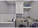 Modern laundry room features a white tiled dog wash, overhead storage, and upscale washer and dryer units at 47 Adalia Ave, Tampa, FL 33606