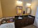 Bathroom featuring a soaking tub, double vanity with granite countertops, and warm lighting at 530 Sandy Hook Rd, Treasure Island, FL 33706