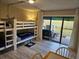 Bright bedroom features a triple bunk bed with wood-look floors and a sliding glass door to a backyard patio at 530 Sandy Hook Rd, Treasure Island, FL 33706