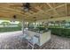Outdoor kitchen area with a grill, bar, ceiling fans, and seating at 530 Sandy Hook Rd, Treasure Island, FL 33706