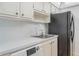 Functional kitchen featuring white cabinetry, stainless sink, and modern black refrigerator at 5967 Terrace Park N Dr # 202, St Petersburg, FL 33709
