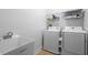 Clean laundry room equipped with a sink, washer, dryer, and storage racks at 6411 Mayra Shores Ln, Apollo Beach, FL 33572