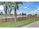 A fenced backyard features a lush lawn, a pond view, and mature palm trees at 811 Eagle Ln, Apollo Beach, FL 33572