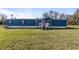 Charming blue home featuring a spacious front yard and a vibrant pink front door at 8428 Highland Pines Ct, Plant City, FL 33565