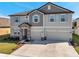 Two story home with a two car garage, light gray paint, stone entryway and shutters on the windows at 8816 Mugnai St, Riverview, FL 33578
