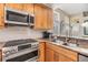 Bright kitchen featuring stainless steel appliances, granite countertops, wood cabinets, and tiled backsplash at 1200 Country Trails Dr, Safety Harbor, FL 34695