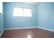 Bedroom with wood floors, large window, and pale blue walls at 13112 Groveland St, Spring Hill, FL 34609