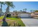 Well-maintained single-story home featuring a manicured lawn, mature palm trees, and a two-car garage at 13112 Groveland St, Spring Hill, FL 34609