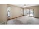 Spacious living room featuring neutral carpet, ceiling fan, and sliding glass doors to the pool area at 13112 Groveland St, Spring Hill, FL 34609