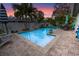 This backyard boasts a beautiful pool, patio seating, and lush landscaping at dusk at 1350 Maple Sw St, Largo, FL 33770