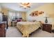 Comfortable bedroom features a ceiling fan, desk with computers, and a bright yellow, decorative bedspread at 19029 Us Highway 19 N # 30H, Clearwater, FL 33764