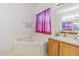 A bright bathroom featuring a corner tub, neutral tile, and a single sink vanity at 20326 Merry Oak Ave, Tampa, FL 33647