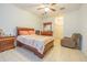 A neutral bedroom features a wooden bed frame, a ceiling fan, and tan tile flooring at 20326 Merry Oak Ave, Tampa, FL 33647