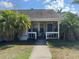 Inviting covered front porch with neutral siding and blue door, framed by lush palm trees on either side at 2218 Egret Walk Ct, New Port Richey, FL 34655