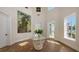 Bright foyer with herringbone wood floors, a glass table with floral arrangement, and a large landscape painting at 2411 And 2407 Casey Key Rd, Nokomis, FL 34275