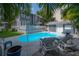 Backyard pool area featuring a charming two-story home, sun loungers, white picket fence, and lush green landscaping at 2921 W El Prado Blvd, Tampa, FL 33629