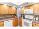 Bright kitchen features honey colored cabinets, a white stove and microwave, and dark countertops at 4470 Meadow Creek Cir, Sarasota, FL 34233