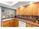 Sunlit kitchen showcasing warm wood cabinetry, stainless sink under window, and tile backsplash at 4470 Meadow Creek Cir, Sarasota, FL 34233