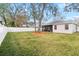 View of a home's back yard with a well-maintained lawn, trees, white fence, and screened patio at 4717 Dunnie Dr, Tampa, FL 33614