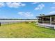 Spacious backyard with manicured lawn, a fire pit, and serene views of the lake at 5325 Sandy Shell Dr, Apollo Beach, FL 33572