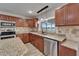 Well-lit kitchen with wooden cabinetry, stone countertops, stainless steel appliances, and a view of the water at 5325 Sandy Shell Dr, Apollo Beach, FL 33572