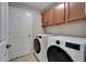 Convenient laundry room featuring a white washer and dryer set, adjacent to wooden cabinets for storage at 5325 Sandy Shell Dr, Apollo Beach, FL 33572