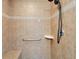 Shower with neutral toned tile, seat, shower head and safety bar at 5325 Sandy Shell Dr, Apollo Beach, FL 33572