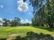 Beautiful golf course with lush green grass and mature trees against a blue sky at 5403 Comanche St, Zephyrhills, FL 33542