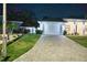 Night view of home showcasing a paved driveway, green lawn, manicured landscaping, and a two-car garage at 809 30Th E Ct, Bradenton, FL 34208