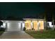 Elegant home featuring an illuminated facade, paver driveway, and manicured lawn at 809 30Th E Ct, Bradenton, FL 34208
