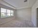Bedroom with natural light from the large window and neutral carpet and trey ceiling at 9244 Bella Vita Cir, Land O Lakes, FL 34637