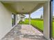Covered back patio with brick pavers, offering a view of the well maintained backyard and blue skies at 10352 Cross River Trl, Parrish, FL 34219