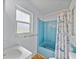 Bright bathroom with a white sink, bathtub with a curtain, and a window providing natural light at 10925 Fort King Rd, Dade City, FL 33525